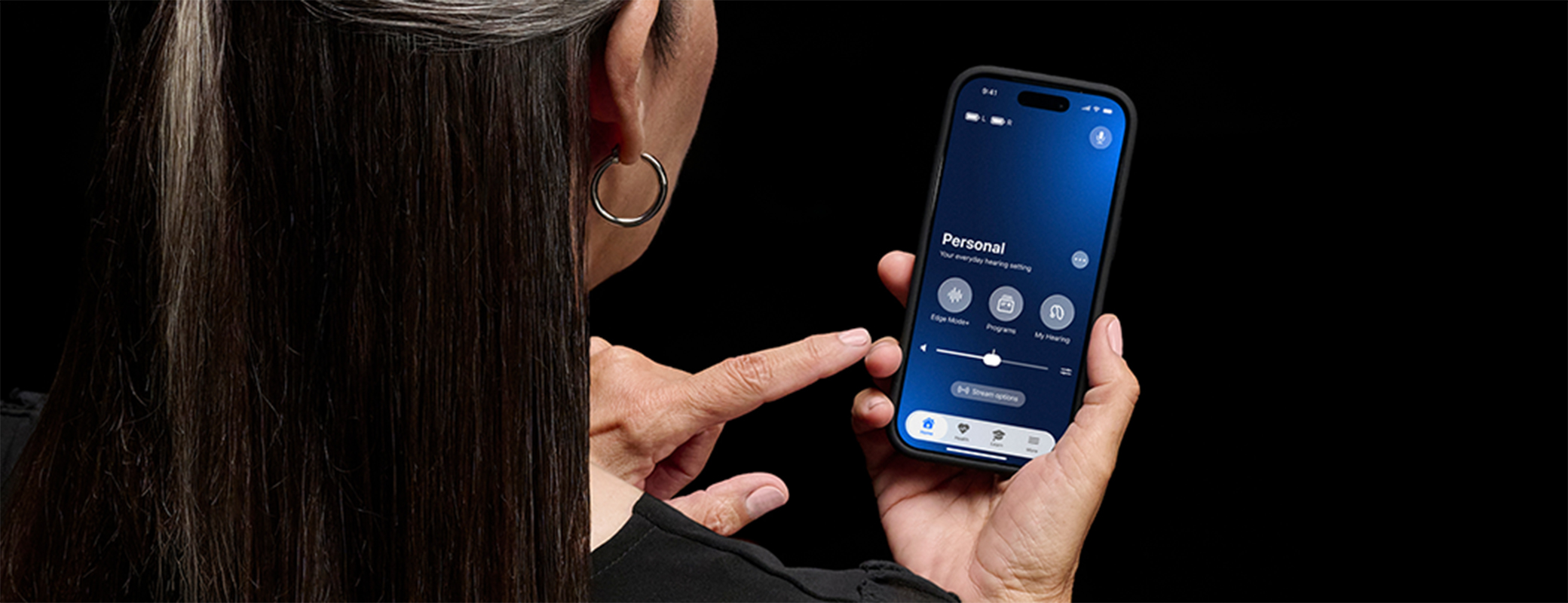 Image of a middle aged woman looking at the My Starkey app home screen on her mobile phone